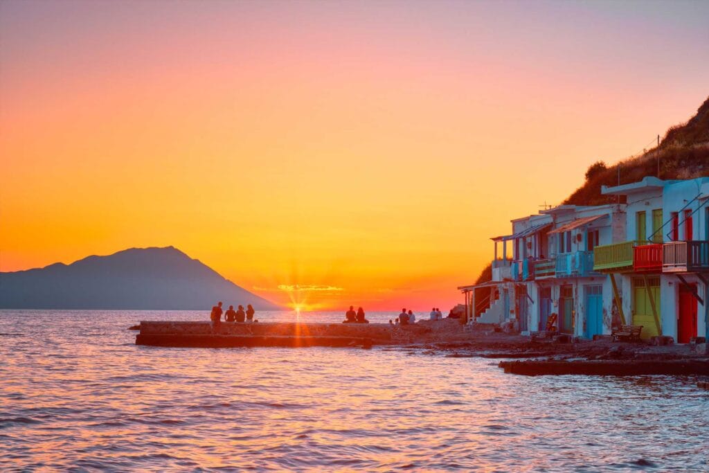 Couple returning to harbour by boat at golden hour in Milos ready for dinner